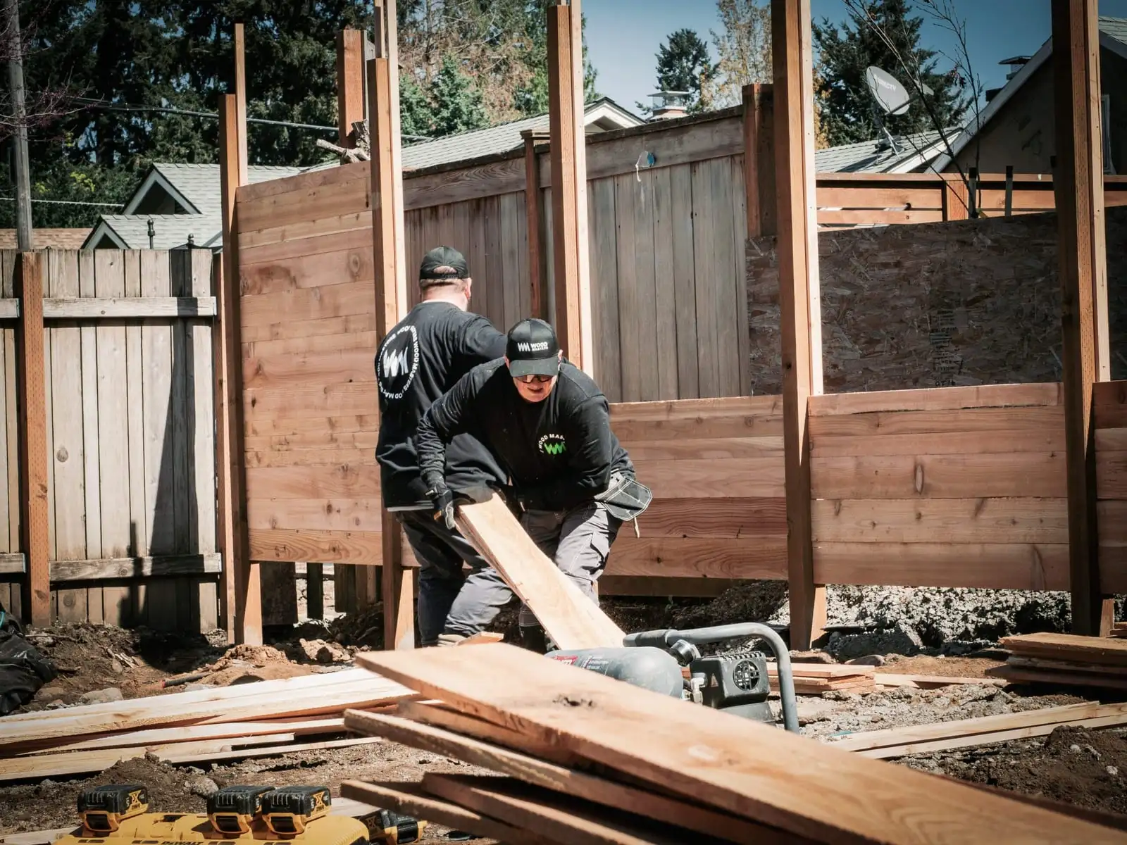 Crew members building a new wood fence in a backyard