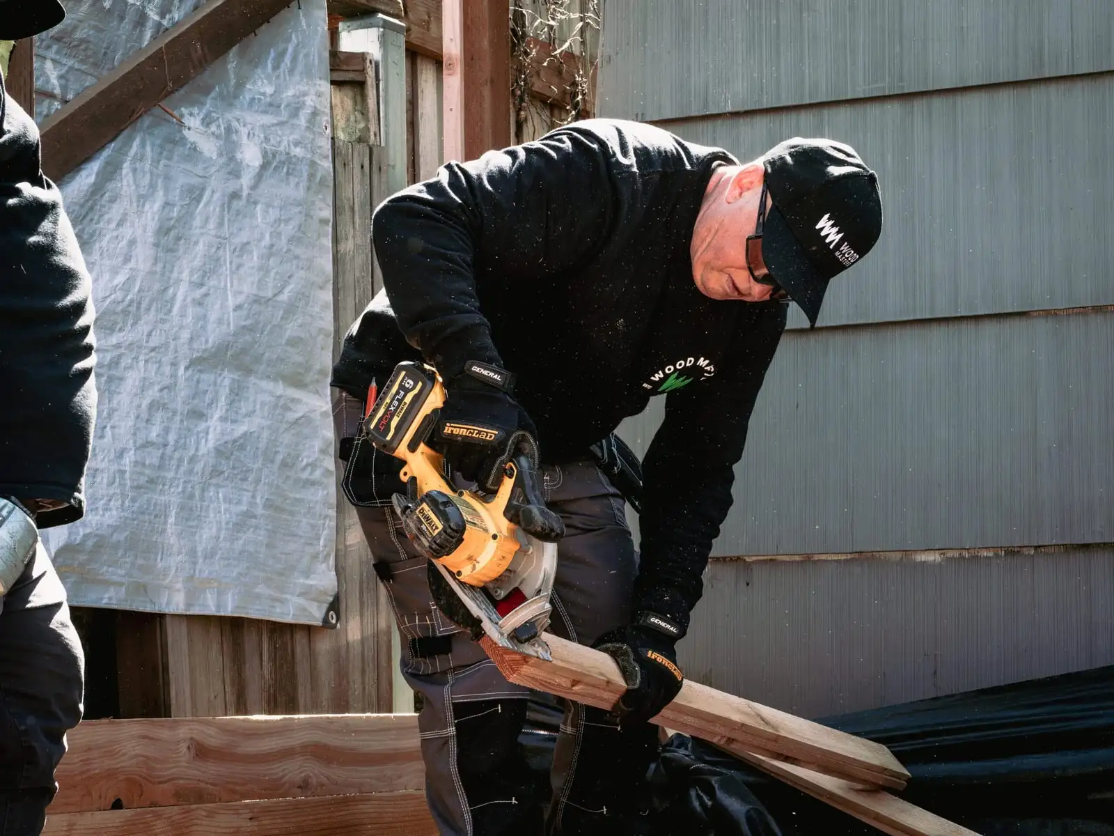 Worker in a Woodmasters cap cutting a board with a circular saw