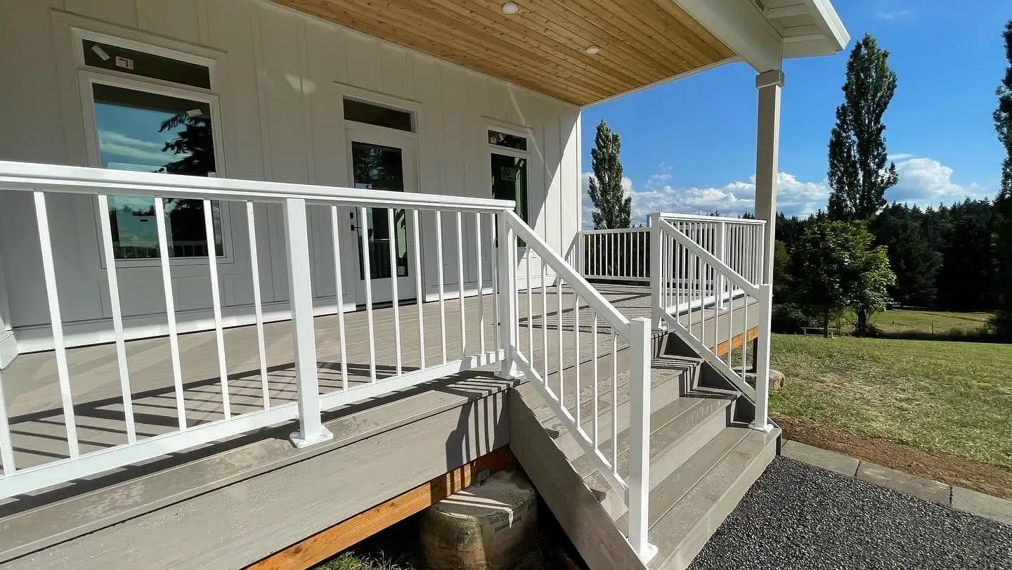Gray composite deck with white railing and stairs on a covered porch