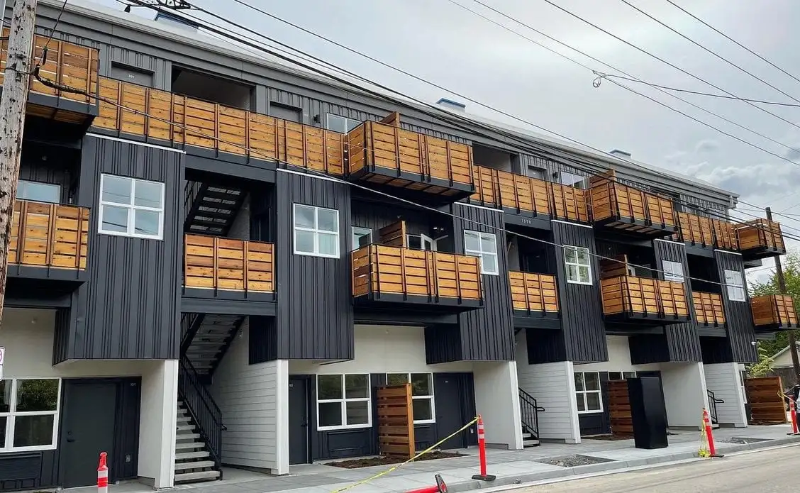 Second-story wood deck with black metal railing above a garage