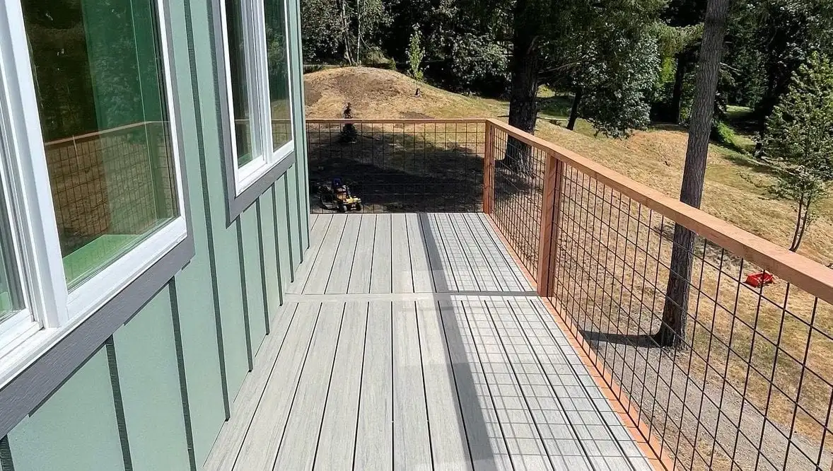 Composite deck with wood-framed wire mesh railing on a green home