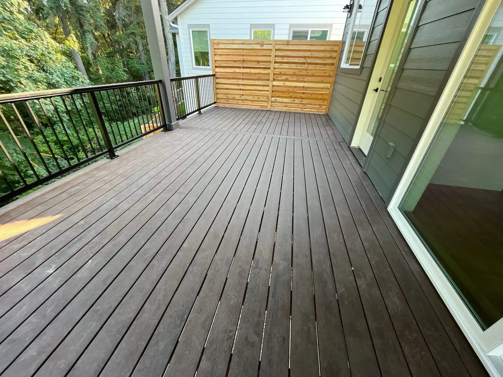Dark composite deck with black aluminum railing and a horizontal privacy screen