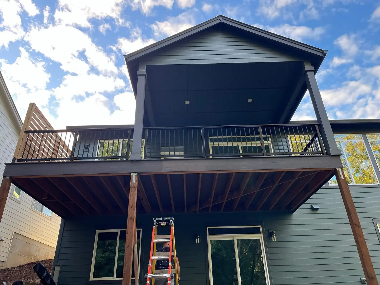 Two-story covered deck with black metal railing on a gray home