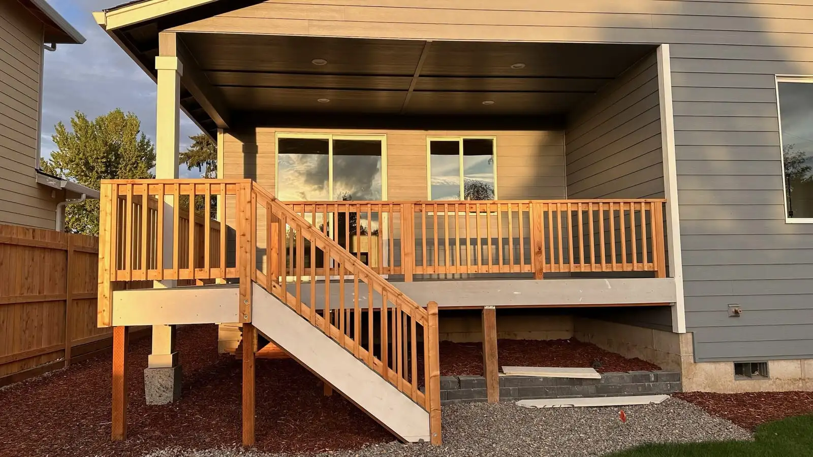 Cedar deck with wood railing and stairs under a covered patio