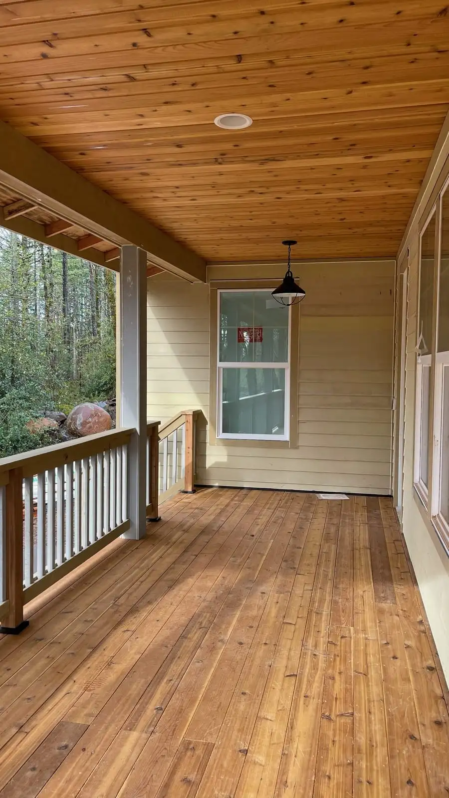 Covered cedar porch deck with a tongue-and-groove ceiling and white railing