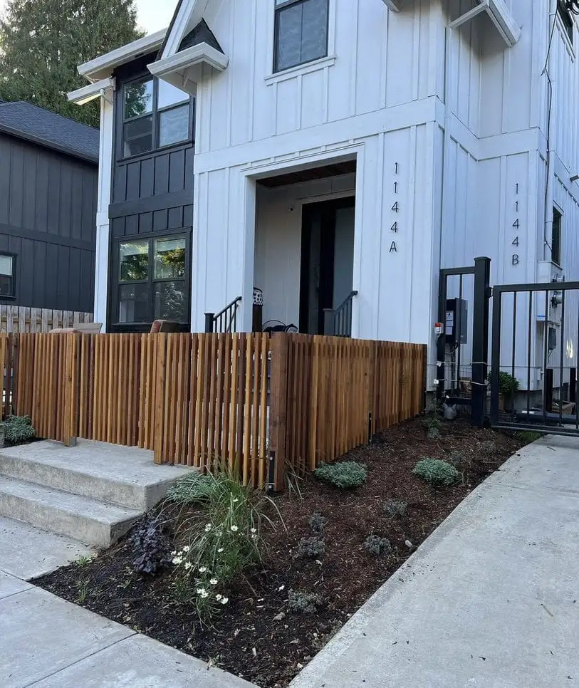 Horizontal cedar fence boards beside a house with white trim and a black-framed window