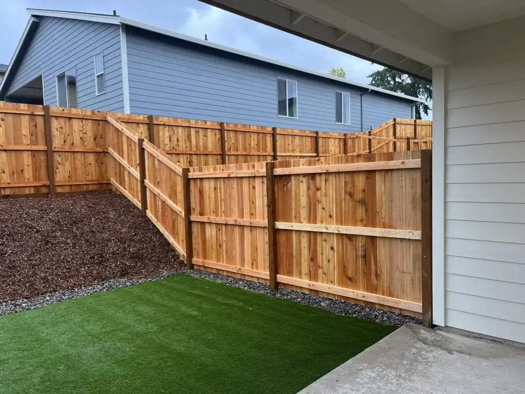 Light natural wood fence with a lattice top along a sidewalk in a residential neighborhood
