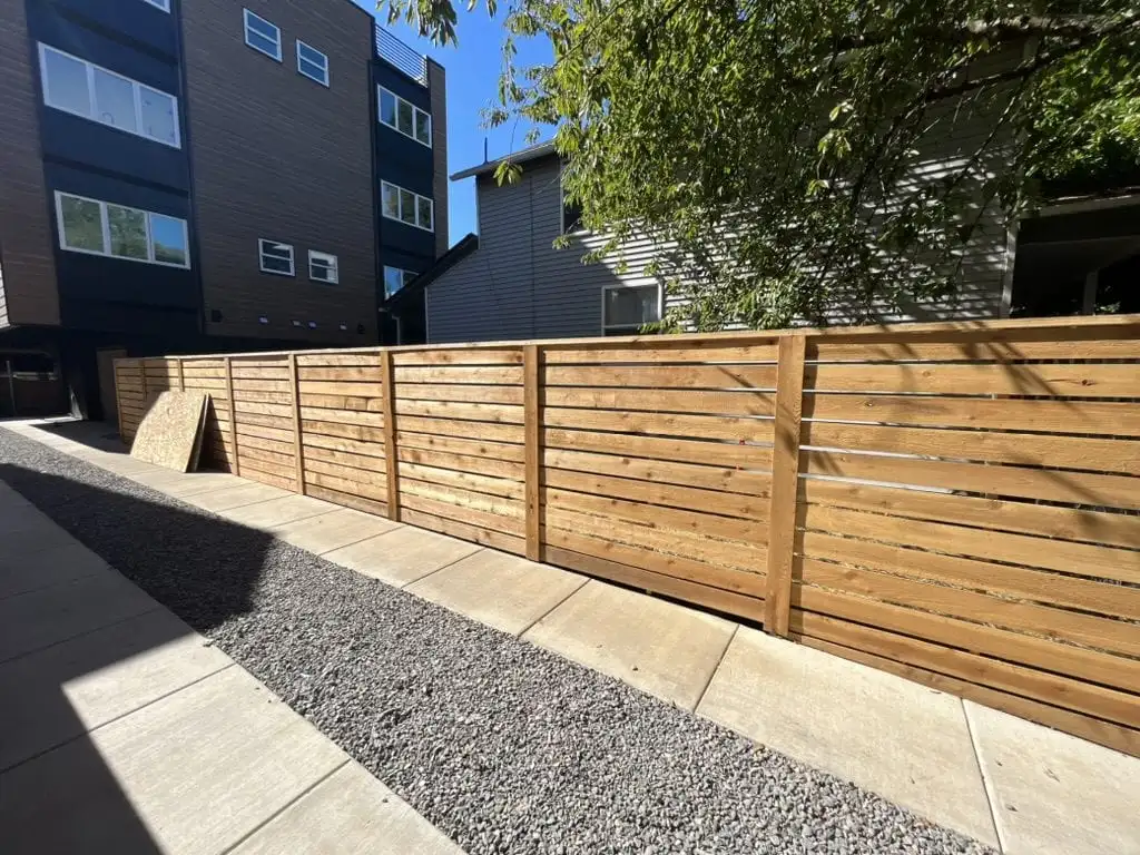 Unstained horizontal cedar fence along the side of a house
