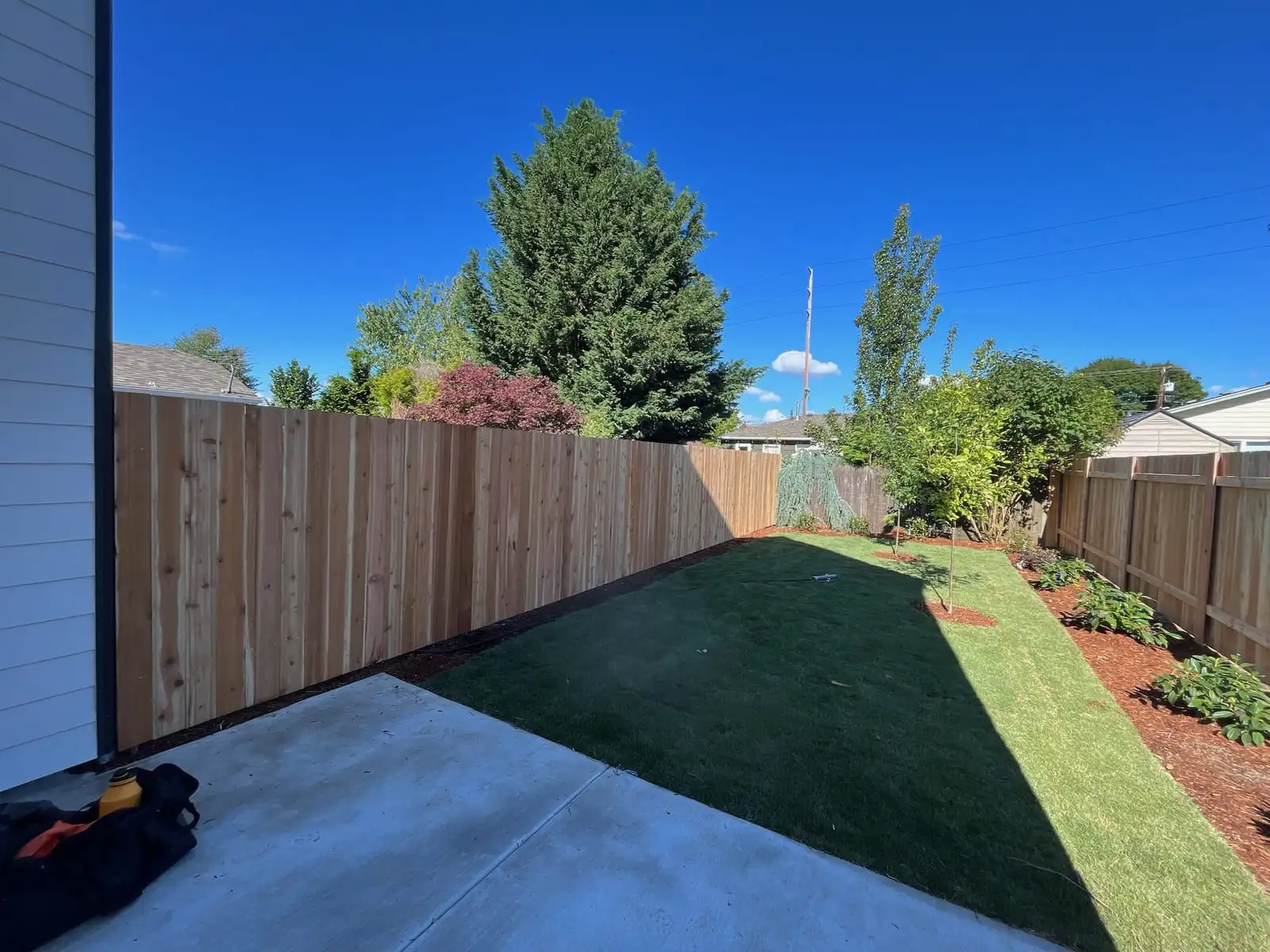 New cedar privacy fence around a backyard lawn and concrete patio in Vancouver, WA