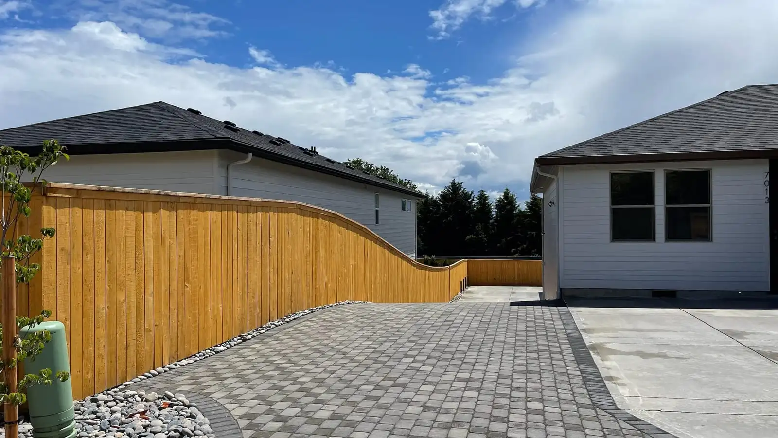 Curved cedar privacy fence along a new paver driveway